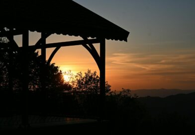 Jak si užít zahradu za každého počasí? Spolehněte s na zahradní pergolu A wooden gazebo silhouette against a warm orange sky and distant mountain ridges
